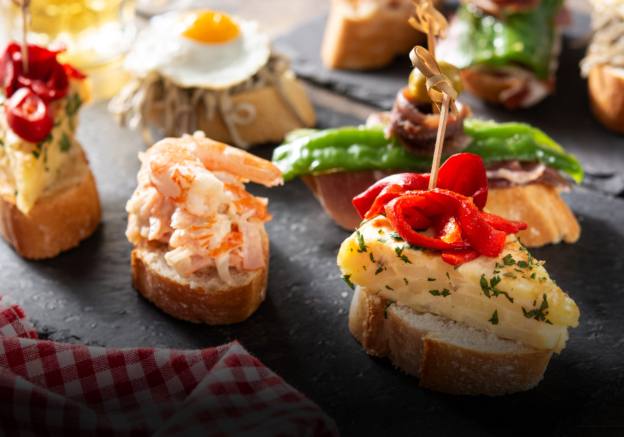 Fem pintxos med sjømat og spekemat – servert med Hiruzta Txakolina 2024 i glasset.
